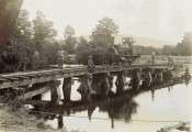 Photograph of members of the Regiment on a temporary railway bridge over a river, with a locomotive on the bridge.